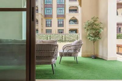 a balcony with two chairs and a building at Souk Al Bahar Luxury stays near poolside with Burj Khalifa view by Norbu Holiday Homes in Dubai