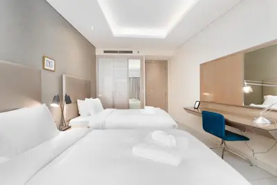 a hotel room with two beds and a desk at Damac Paramount Tower Burj Views in Dubai