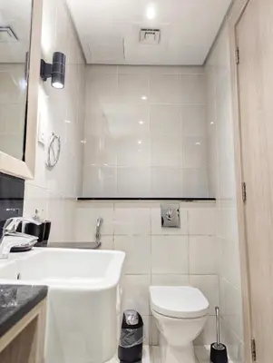 a white bathroom with a toilet and a sink at Waterfront Studio with Burj Khalifa & Dubai Mall Access, Walk to Dubai Water Canal & Business Bay Metro in Dubai