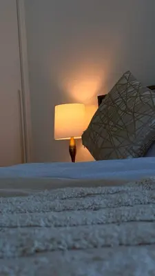 a bed with a lamp sitting next to a pillow at Brand New Golf View - Luxe Nest at Dubai Hills one bedroom apartment in Dubai