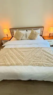 a large white bed with two lamps on two tables at Brand New Golf View - Luxe Nest at Dubai Hills one bedroom apartment in Dubai