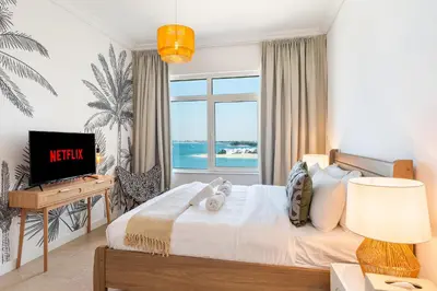 a bedroom with a bed and a tv and a window at BURJ views Private Beach 2 Bedroom Apartment with panoramic Sea View and Pool Palm Jumeirah in Dubai