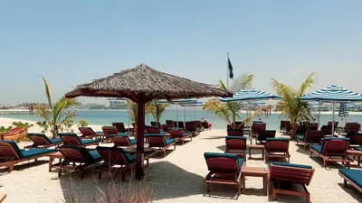 a bunch of chairs and umbrellas on a beach at BURJ views Private Beach 2 Bedroom Apartment with panoramic Sea View and Pool Palm Jumeirah in Dubai