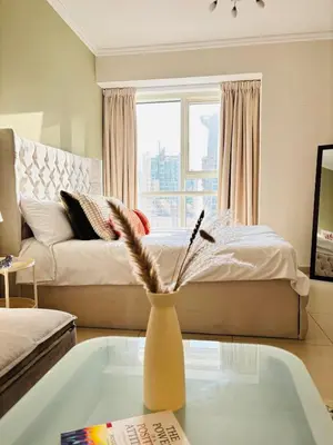 a living room with a bed and a vase on a table at ZenStay - Cozy Studio with City Views in Dubai