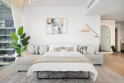 a white bedroom with a bed and a couch at Marina Gate Luxury Full Marina & Sunset Sea Views in Dubai