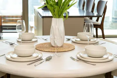 a table with plates and glasses and a vase with flowers at Marina Gate Luxury Full Marina & Sunset Sea Views in Dubai