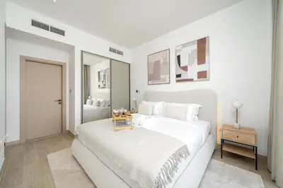 a white bedroom with a large white bed and a table at Marina Gate Luxury Full Marina & Sunset Sea Views in Dubai
