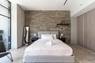 a bedroom with a large bed and a brick wall at HAVN - Modern Studio in JVC with Huge Layout in Dubai