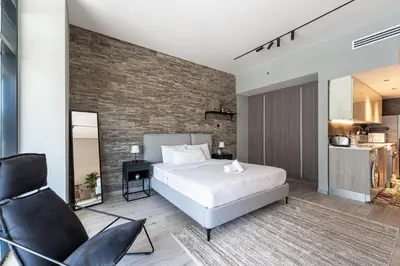 a bedroom with a white bed and a brick wall at HAVN - Modern Studio in JVC with Huge Layout in Dubai