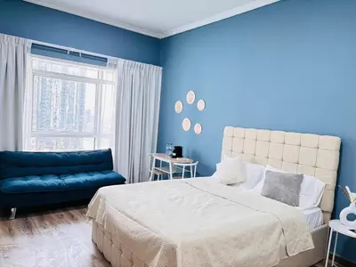a blue bedroom with a bed and a couch at ZenStay-Stylish Studio 1 Min to Metro in JLT in Dubai