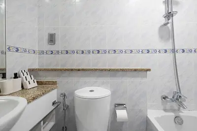 a white bathroom with a toilet and a sink at Lake View Studio near Marina with Pool, Balcony and Gym in Dubai