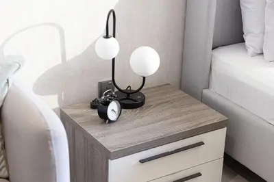a bedside table with a clock and two lamps on it at Lake View Studio near Marina with Pool, Balcony and Gym in Dubai