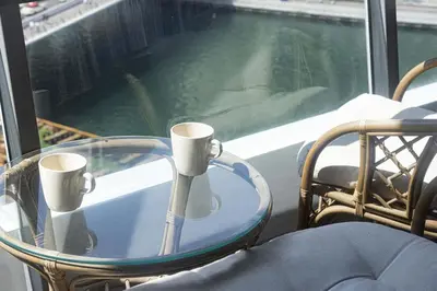 a glass table with two cups on it in front of a window at Waterfront Studio, perfectly located in Dubai Marina in Dubai
