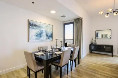 a dining room with a black table and chairs at Livbnb- Coastal 2B with Marina View Walk to Beach in Dubai