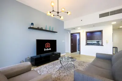 a living room with two couches and a tv at Livbnb - High Floor 2B with Marina View Walk to Beach in Dubai
