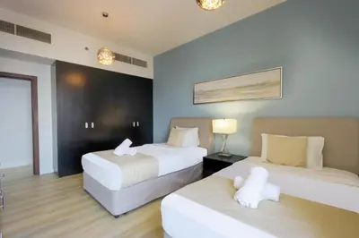 a hotel room with two beds and a lamp at Livbnb - High Floor 2B with Marina View Walk to Beach in Dubai