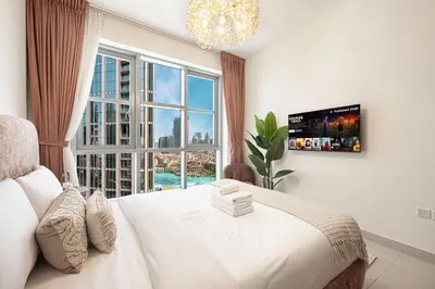a bedroom with a white bed and a large window at Splendid 2BR Burj Khalifa & Fountain view in Dubai