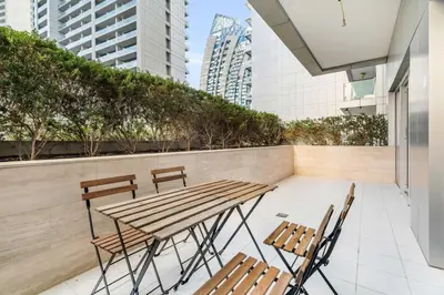 a wooden table and chairs on a balcony with buildings at GuestReady - Luxe Comfort in Bussiness Bay in Dubai