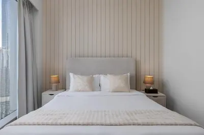a bedroom with a large white bed with two lamps at Maison Privee - Sky-High Elegance with Unrivaled Burj Khalifa Views in Dubai