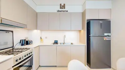 a kitchen with white cabinets and a stainless steel refrigerator at Enjoy Best Burj Khalifa & Fountain Views From Balcony Luxury 2BR 3 Mins from Dubai Mall - Like Home in Dubai