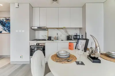 a white kitchen with a table with plates and wine glasses at GuestReady - Luxe Residence in Dubai Marina in Dubai