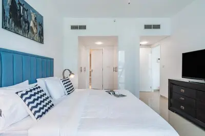 a bedroom with a large white bed with a flat screen tv at Luxury 2BR Stay in DIFC, Steps to Gate Avenue and Dubai Mall in Dubai