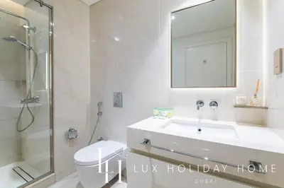 a bathroom with a sink and a toilet and a mirror at LUX The Beach Vista Dubai Eye View Suite in Dubai