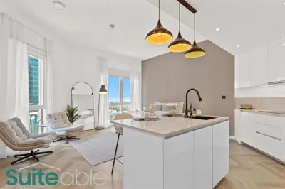 a kitchen with white cabinets and a kitchen island at Spacious refurbished Studio steps away from metro in Dubai