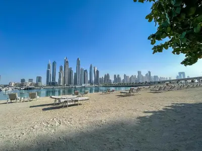 a beach with tables and chairs in front of a city at Breathtaking Elegance 1Bedroom in Emaar Beachfront in Dubai
