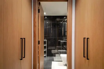 a bathroom with two wooden doors and a toilet at Luxury 1BR at Binghatti Onyx JVC in Dubai