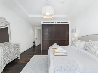 a white bedroom with a large bed and a mirror at Short stay Limestone House DIFC 2 bedrooms in Dubai
