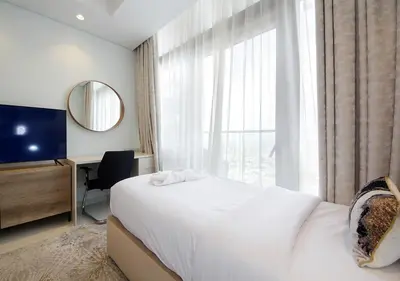 a bedroom with a bed and a desk and a large window at The Perfect Stay Paramount Business Bay 2BR in Dubai