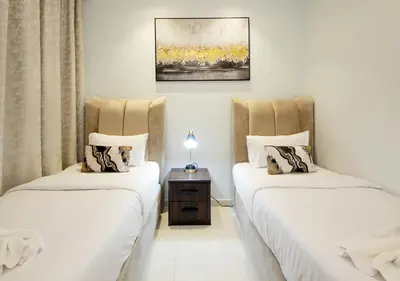 two twin beds in a room with a table at The Perfect Stay Paramount Business Bay 2BR in Dubai