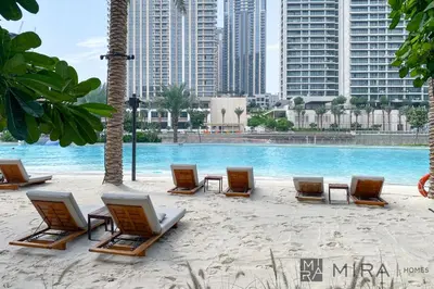 a group of lounge chairs and a pool with buildings at Mira Holiday Homes - Cosy 1BHK in the heart of Dubai Creek Harbour in Dubai