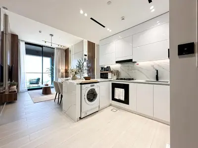 a kitchen with white cabinets and a washer and dryer at Trophy-Cultivate Retreat with Statement Design in Dubai