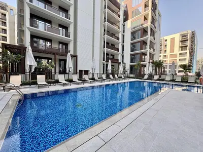 a swimming pool with chairs and umbrellas next to a building at FIRST CLASS 1BR Glamorous & Stylish Escape in Dubai
