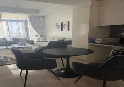 a living room with a table and chairs and a couch at Aykon city 2BHK beach city view in Dubai