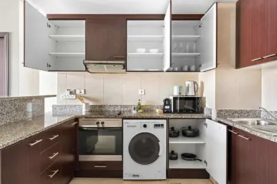 a kitchen with a washing machine and a sink at Silkhaus Premium 1BR at Sky Gardens in Heart of DIFC in Dubai