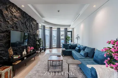 a living room with a blue couch and a tv at RP Heights - Luxe 2BR with Burj Khalifa View - Zed Living in Dubai