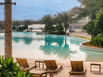 a swimming pool with two chairs and a table at Elegant 1 Bedroom in Orchid at Creek Beach in Dubai