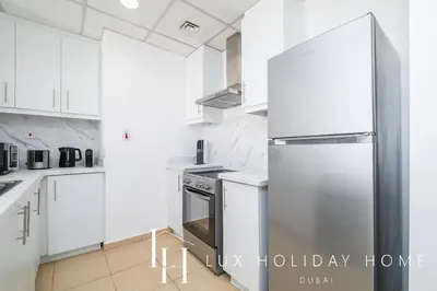 a kitchen with white cabinets and a stainless steel refrigerator at LUX The Dubai Eye View JBR Studio in Dubai