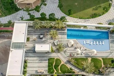 an overhead view of a swimming pool and a building at Stylish Fully Furnished 1BH Apartment Close by Dubai Science Park, Dubai Miracle Garden and Butterfly Garden in Dubai