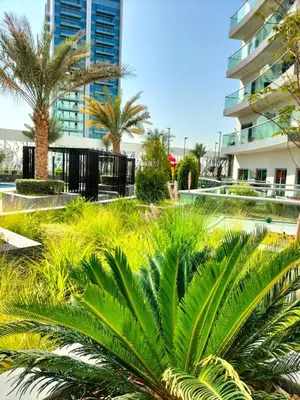 a park with palm trees and a building at Stylish Fully Furnished 1BH Apartment Close by Dubai Science Park, Dubai Miracle Garden and Butterfly Garden in Dubai