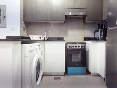 a kitchen with a washing machine and a stove at Stylish Fully Furnished 1BH Apartment Close by Dubai Science Park, Dubai Miracle Garden and Butterfly Garden in Dubai