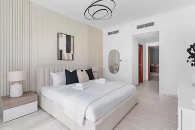 a white bedroom with a large bed and a mirror at Silkhaus Residences Towers 3BR Near Burj Khalifa in Dubai