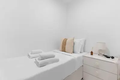a white bedroom with a bed and a dresser at Silkhaus Residences Towers 3BR Near Burj Khalifa in Dubai