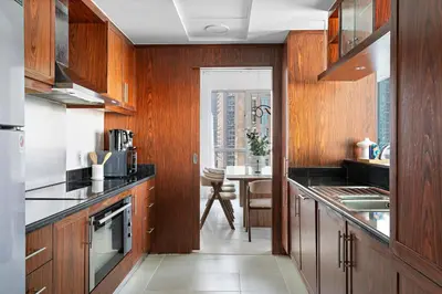 a kitchen with wood paneled cabinets and a table at Silkhaus Residences Towers 3BR Near Burj Khalifa in Dubai
