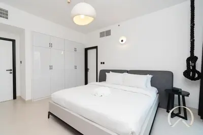 a white bedroom with a large bed with white sheets at Upgraded 2BR In La Riviera Marina - Close to Beach in Dubai