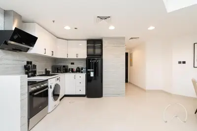 a kitchen with a black refrigerator and white cabinets at Upgraded 2BR In La Riviera Marina - Close to Beach in Dubai