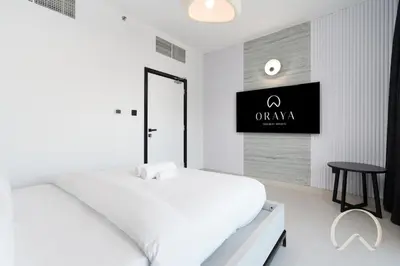 a white bedroom with a bed and a tv on the wall at Upgraded 2BR In La Riviera Marina - Close to Beach in Dubai